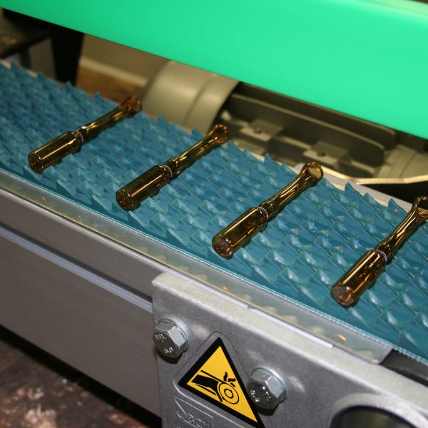 Transport of ampoules on a saw-tooth belt material.